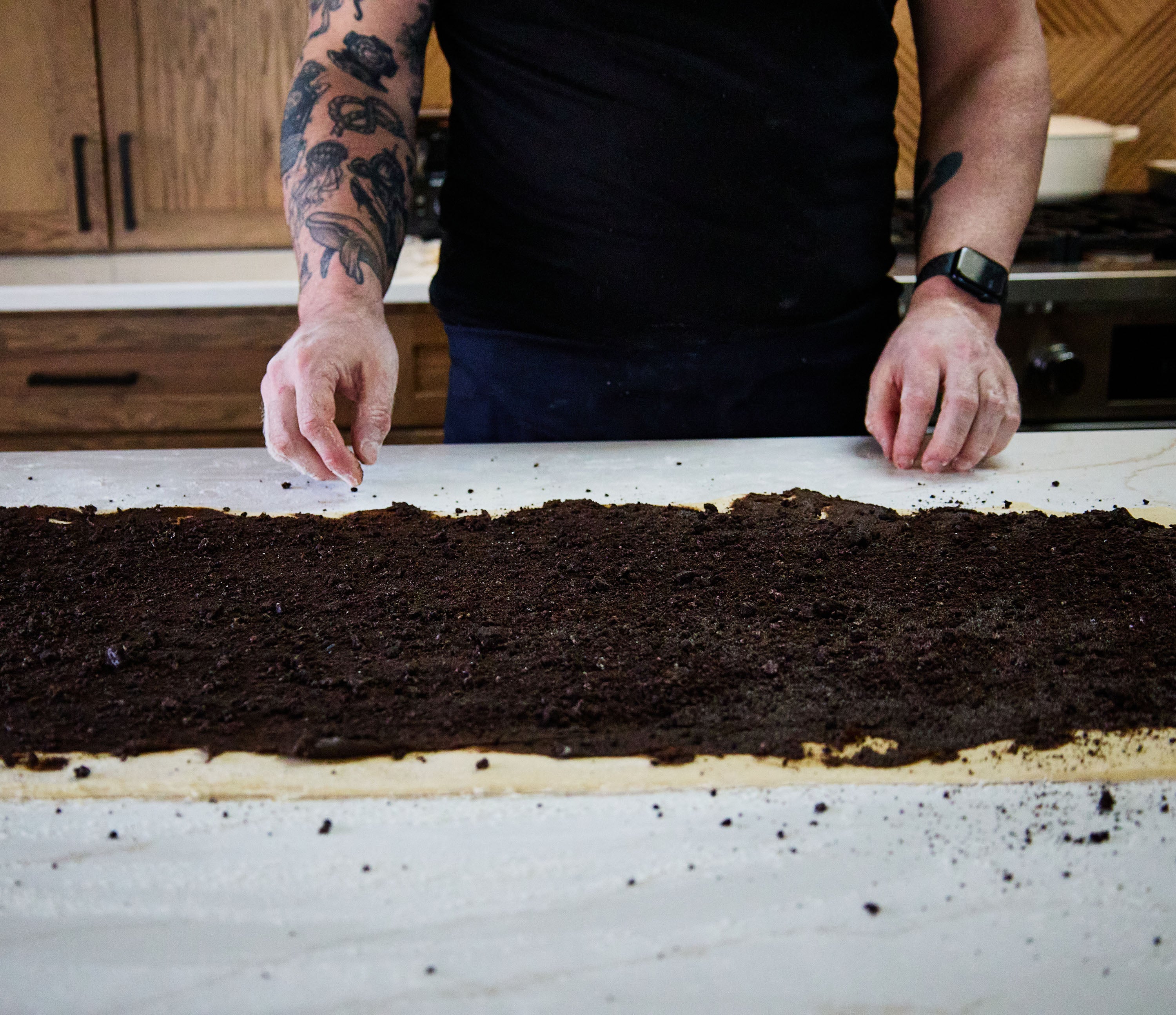 Person preparing oreo cinnamon rolls on a kitchen counter.