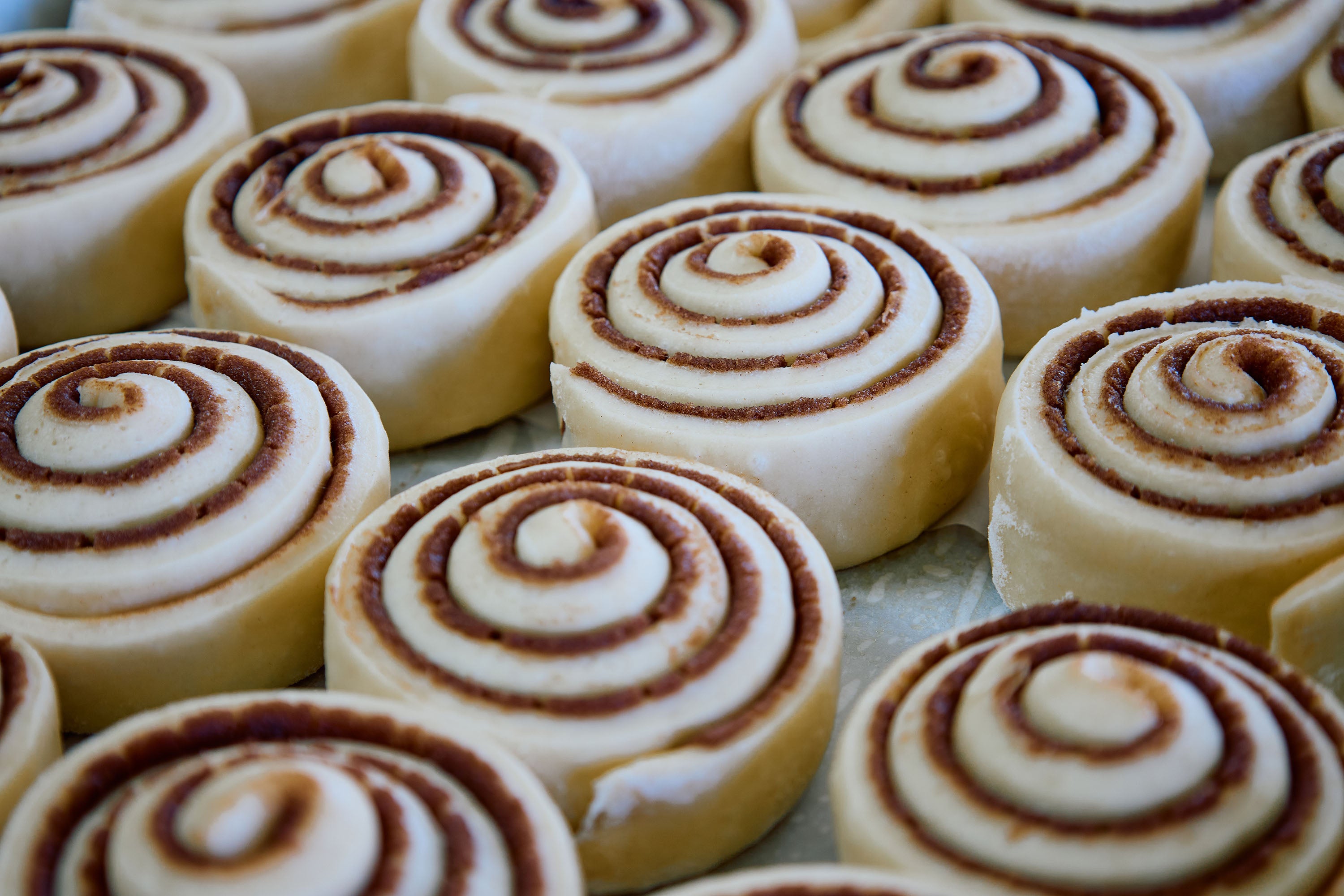 Cinnamon roll dough with visible swirl pattern on a baking sheet.