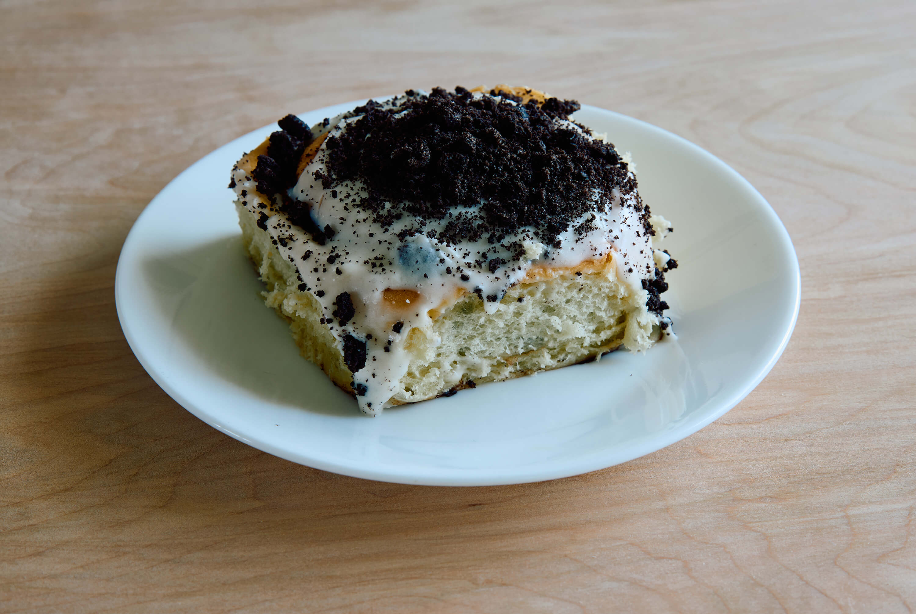 oreo cinnamon roll with vanilla bean frosting and oreo crumbs
