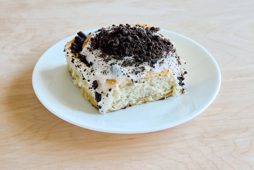 oreo cinnamon roll with vanilla bean frosting and oreo crumbs