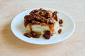 Cinnamon roll with pecans on a white plate on a wooden table